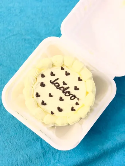 A sweet and simple bento cake with the word "Ladoo" (a term of endearment) surrounded by hearts.