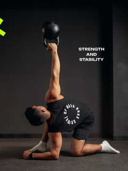 A coach performs a kneeling Turkish get-up with a kettlebell, a complex movement that builds total-body strength and stability.