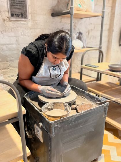 Finding her rhythm on the wheel. Our instructors are always on hand to guide you, ensuring your first pottery experience is a successful and enjoyable one.
