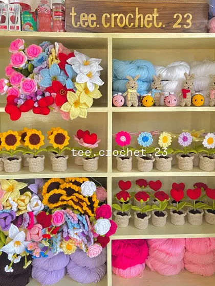 A wide view of my workshop shelves, showcasing a mix of potted flowers, amigurumi, and yarn.