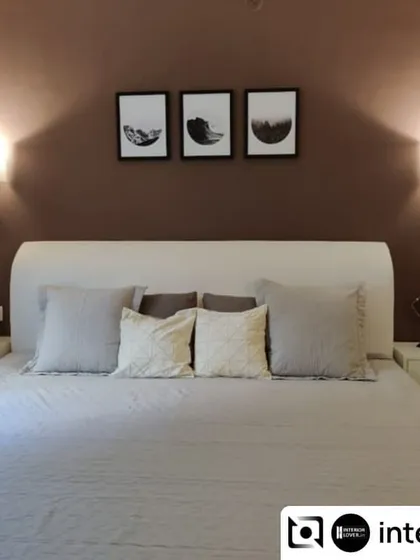 A simple and serene guest bedroom. The design uses a muted color palette with a deep brown accent wall and elegant wall sconces to create a warm and welcoming space for visitors.
