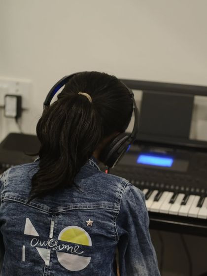 A student from behind, wearing headphones and focused on her keyboard. Our classes are designed for deep concentration and individual progress.