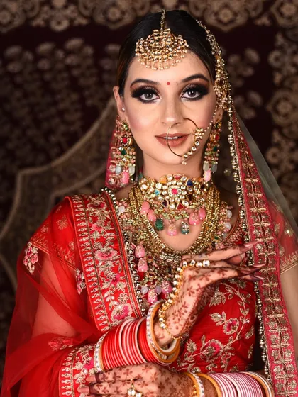 This bride chose a vibrant red lehenga and complemented it with a stunning, multi-layered Polki necklace with colorful pastel drops. A perfect example of creating a custom look through our rental service.