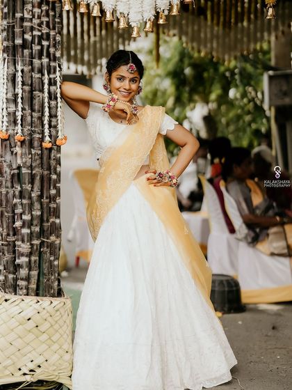 A smiling bride posing next to sugarcane stalks, part of the traditional decor for her Haldi ceremony.