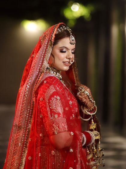 A full-view of the bride in her gorgeous red lehenga, showcasing a complete and cohesive look.