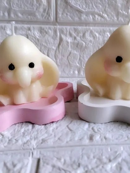 A pair of my baby elephant soy wax candles, one in pink and one in white, resting on decorative trays. These are perfect as Ganpati or baby shower return favors.