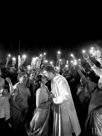 A kiss under the light of a hundred phones. This candid shot captures the couple's private moment in a public celebration, a modern take on a classic wedding memory.