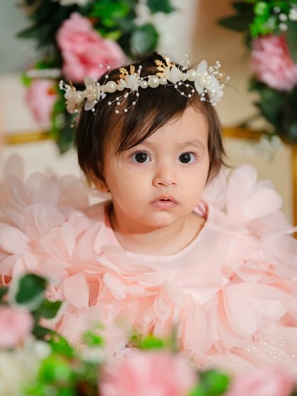 A direct and engaging portrait of the birthday girl in her floral setting. Her curious eyes and sweet expression are the heart of this photograph.