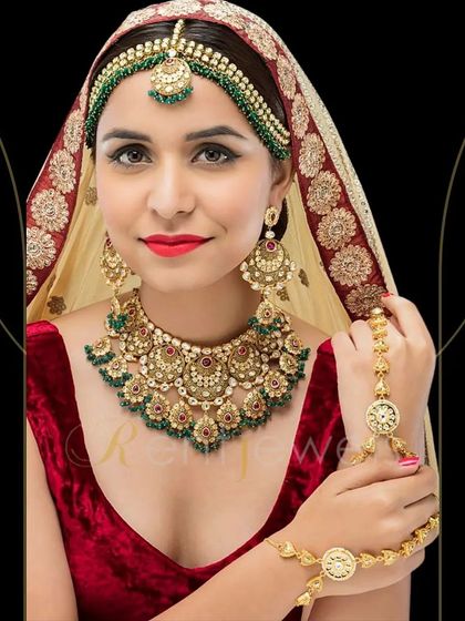 This Polki Kundan bridal set features beautiful red and green Meenakari work. It's a complete set that includes the choker, earrings, mathapatti, and hathphool, perfect for a traditional bride.
