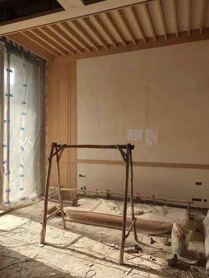 An interior view of the DLF Phase 1 residence, showing the installation of wooden ceiling rafters and wall paneling, key elements of its minimalistic design.