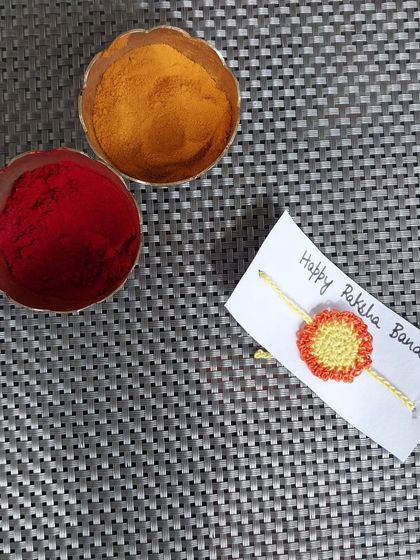 A simple flower-like crochet rakhi in orange and yellow. These are affordable and can be ordered in large quantities.