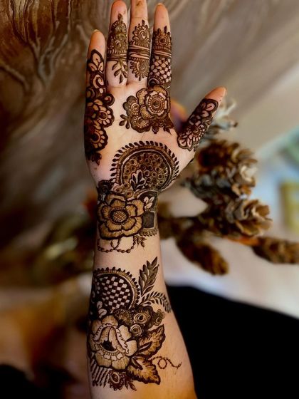 A beautiful example of a Dubai-style mehndi design. It combines elements of Arabic vines, Indian patterns, and geometric checkerboards for a full and intricate look that covers the entire hand and wrist.