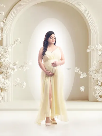 A full-length portrait in a lovely pale yellow gown against a bright, architectural white backdrop. The soft lighting and elegant pose create a serene and graceful image.