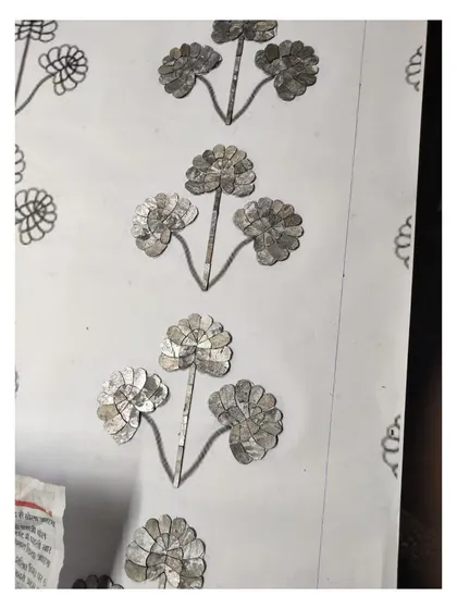 A detailed shot of the Thikri glass pieces being applied to the backing, following the hand-drawn floral pattern.