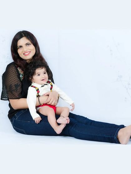 A relaxed and happy portrait of a mother and her baby. The casual denim and simple background keep the focus on their sweet interaction.