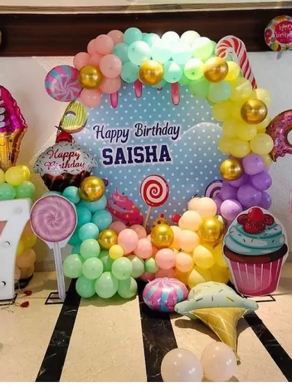 A sweet candy-themed 7th birthday party. The decor includes a custom backdrop, large candy and ice cream props, and a marquee number '7'.