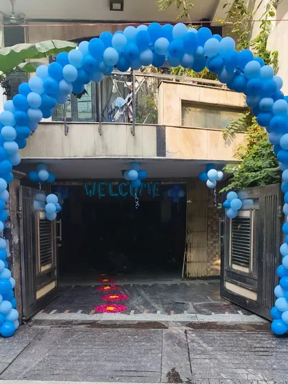 A large blue balloon arch at the main gate of the house, announcing the arrival of a baby boy to the neighborhood.
