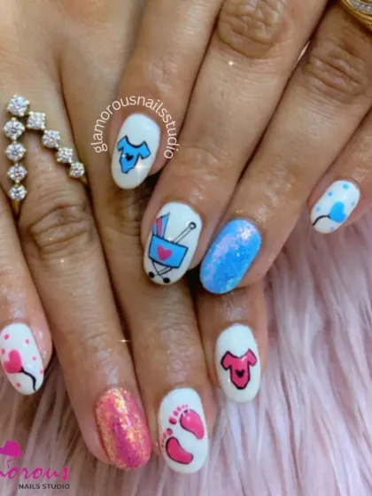 A full set of adorable baby shower nails! We used a white base to make the pink and blue hand-painted art pop, featuring tiny clothes, a stroller, and little footprints. The glittery pink and blue accent nails add the perfect amount of sparkle.
