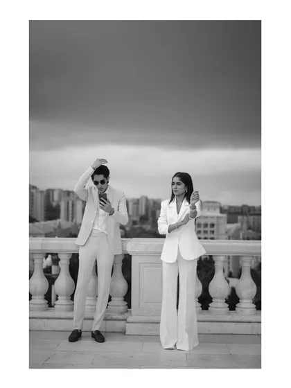 A stylish, full-length black and white portrait against the dramatic sky of Baku. Their confident poses and coordinated white suits give this photo a cool, editorial feel.