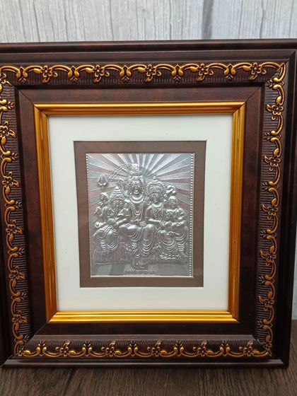 A 999 pure silver frame of the Shiva Parivar, a beautiful depiction of Lord Shiva, Goddess Parvati, and Ganesha, set in a decorative wooden frame.