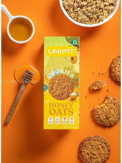 A Unifit honey oats cookie box, styled with a honey dipper and oats for a natural, healthy feel.
