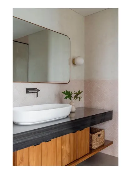 A soothing bathroom featuring a custom wood vanity with a dark stone top. The simple, clean lines and natural materials create a calm, spa-like atmosphere.