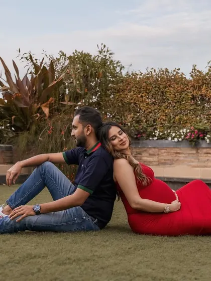 A serene and supportive pose, with the couple sitting back-to-back, connected and peaceful in a beautiful garden setting.