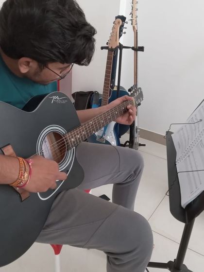 A student practicing a song on his acoustic guitar.