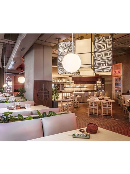 The long view down the restaurant highlights the thoughtful seating layout, with comfortable booth seating separated by planters. This arrangement provides privacy and a connection to nature within the bustling environment.