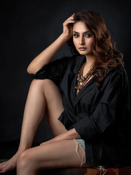 A moody studio portrait with a dark background. The lighting is focused on the model's face and the intricate statement necklace, creating a sense of intimacy and intensity.