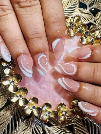 An elegant abstract design with white swirls over a sheer pink base on oval-shaped nails.