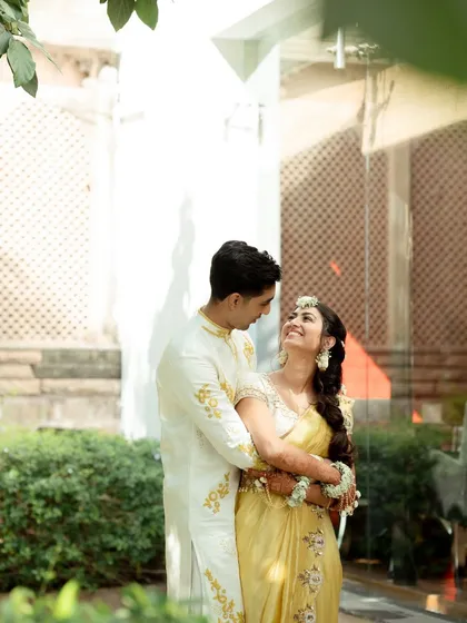 A tender moment between the couple during their Haldi ceremony photoshoot in Udaipur. The lush green background complements their traditional yellow outfits perfectly.