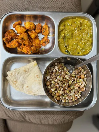 A meal with chapati, sprouts salad, chicken tikka, and a vegetable curry. This is a high-protein and fiber-rich plate.