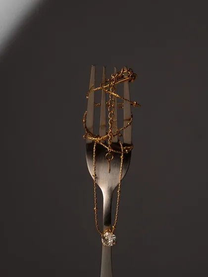 An unconventional jewelry shot, with gold chains and rings wrapped around a fork. This surprising and artistic concept is guaranteed to stop the scroll and make an impression.