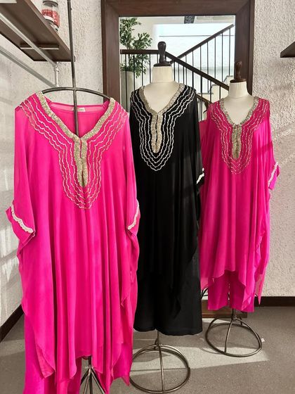 A trio of elegant kaftans in fuchsia and black, all featuring a distinctive scalloped and embroidered neckline.