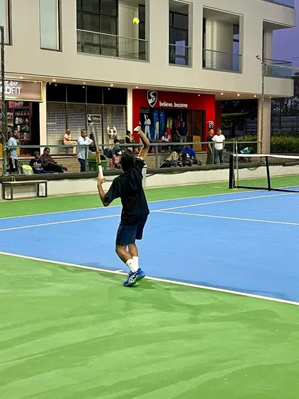 A player executes a powerful overhead smash during a tournament. We train all aspects of the game, including aggressive net play and finishing shots.