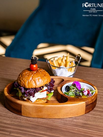 A closer look at our gourmet burger, served on a wooden platter with a side of crispy fries and fresh salad.