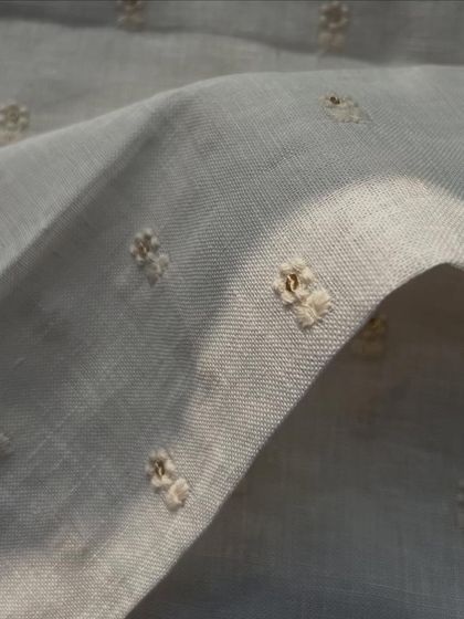 A close-up of our embroidered gauge linen, showing the small, delicate buti embroidery. This dyeable fabric is perfect for creating subtle, textured garments.