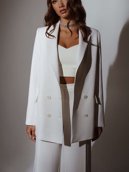 This white double-breasted blazer is paired with a matching crop top and trousers, showing how you can style a power suit for a more contemporary, edgy vibe.