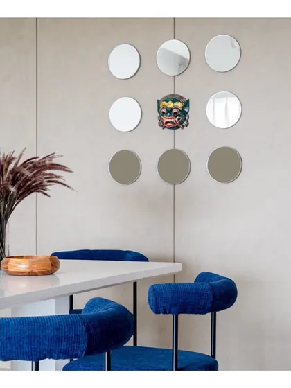 The smaller quirks often make a space unique. Here, a collection of small, round mirrors and a traditional mask add a touch of playful personality to a modern dining corner.