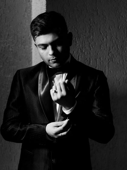 A classic black and white portrait of the groom adjusting his cufflinks, exuding timeless style and sophistication.