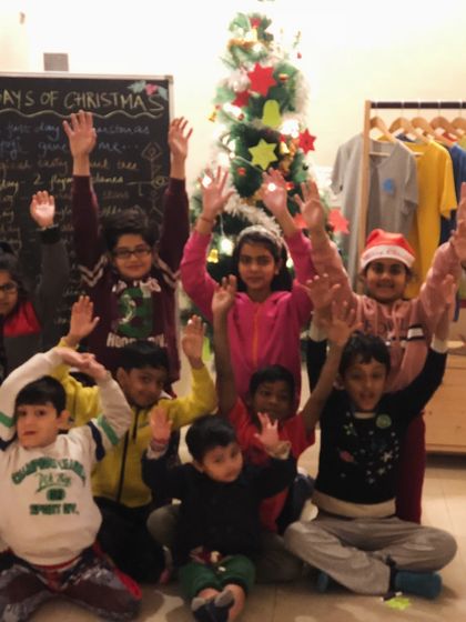 A happy group of children wave in front of a Christmas tree after a fun filled day of yoga and activities.
