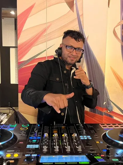 Giving a shaka sign to the crowd from behind my Pioneer DJ setup. It's all about good vibes and great music.