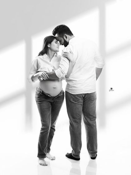 A full-length view of a tender embrace, captured in classic black and white. The simple styling with jeans and white shirts keeps the focus purely on the couple's emotional bond.