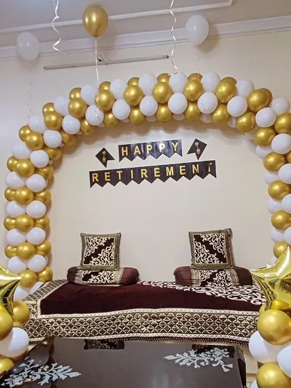 I also handle decorations for important career milestones like retirement parties. This elegant setup features a classic gold and white balloon arch over the main seating area, with a 'Happy Retirement' banner and star-shaped foil balloons.