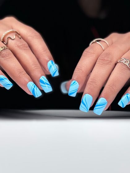 The full two-hand set of the graphic blue swirl nails. The design is consistent and eye-catching, perfect for someone with a fun and modern style.