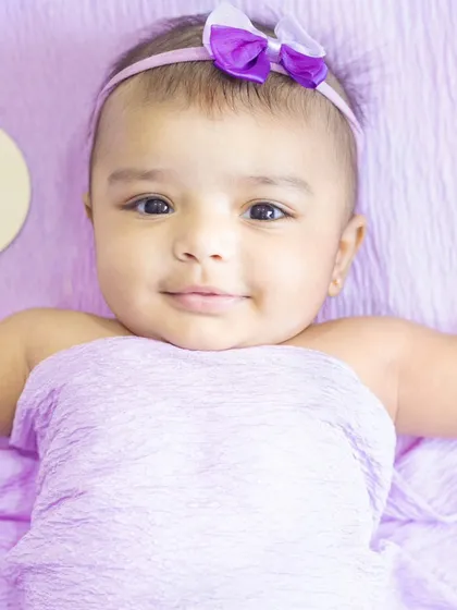 A calm and gentle portrait of a baby girl with a 'Hello World' milestone card. These sessions are perfect for tracking your baby's growth.