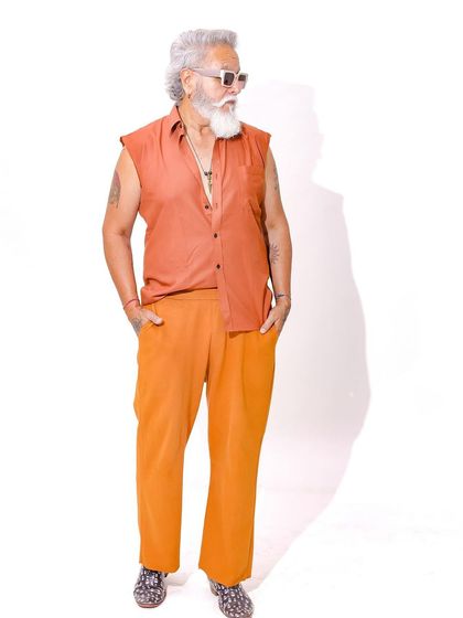 A vibrant, high-key studio shot featuring a senior model in a colorful, sleeveless shirt and orange pants, perfect for a summer campaign.