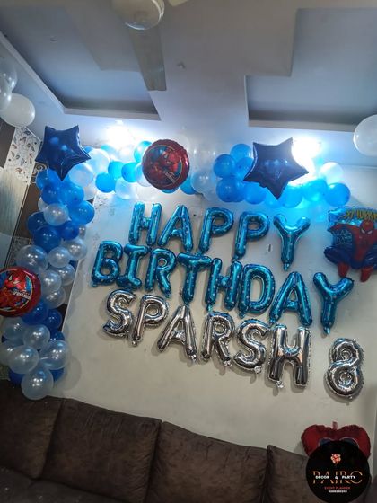 A Spider-Man themed birthday decoration for a home celebration, with large foil letter balloons for the name and age.