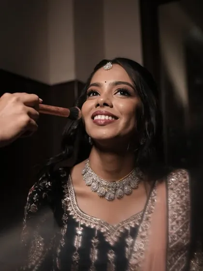 A happy smile during the final touches is the best reward. This behind-the-scenes moment captures the joy and excitement of getting ready. I am applying a light blush to create that perfect, natural-looking flush for her reception.